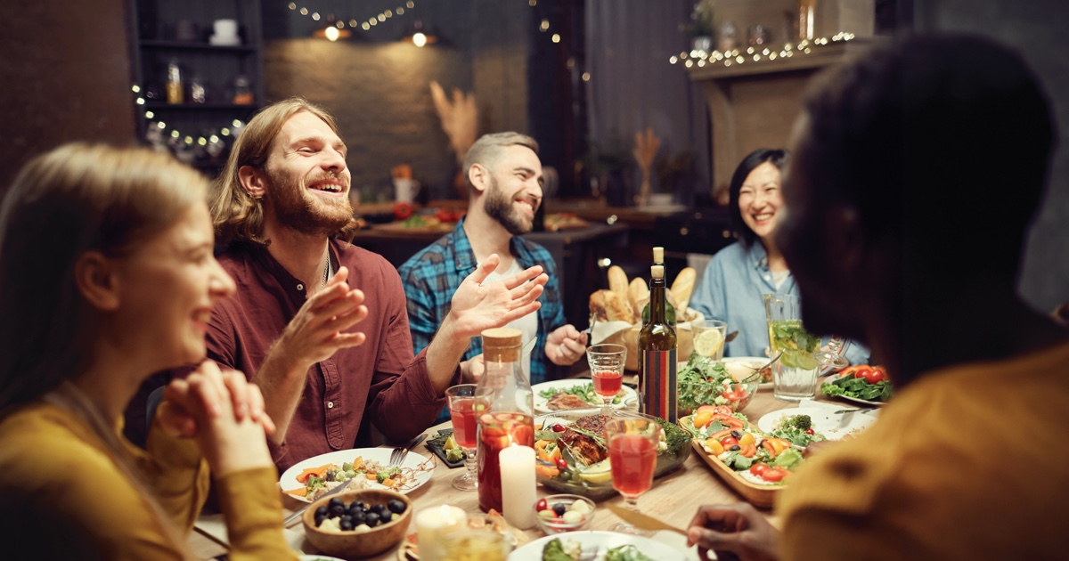Friends gathered around the table enjoying a pork meal.